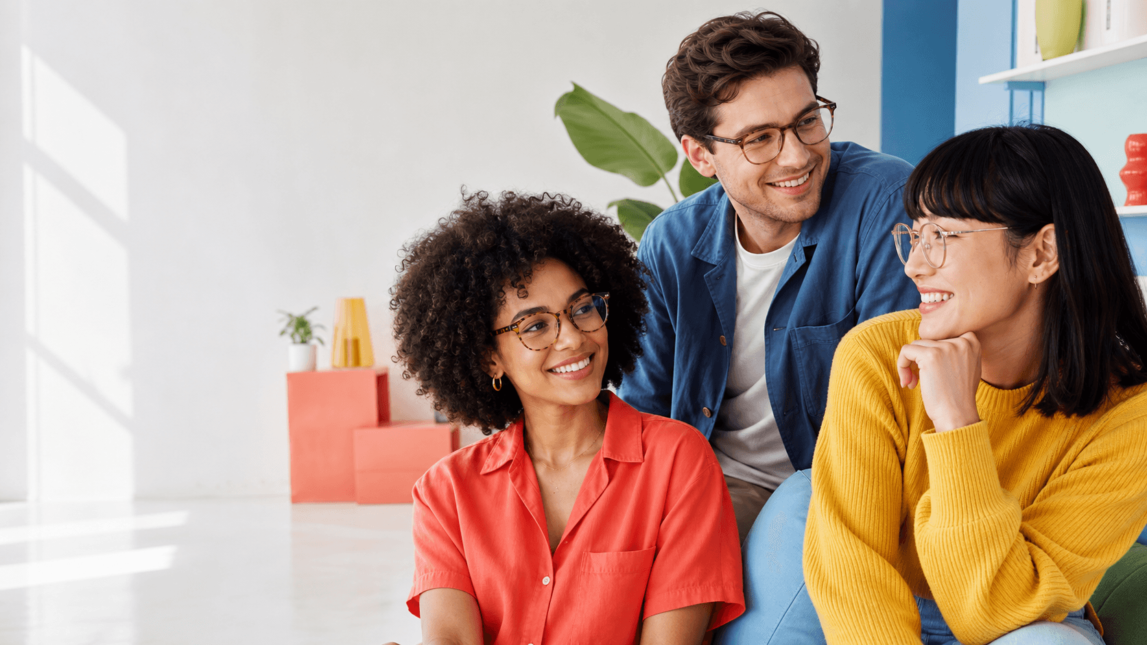 Three adults wearing contemporary eyeglasses in a bright studio